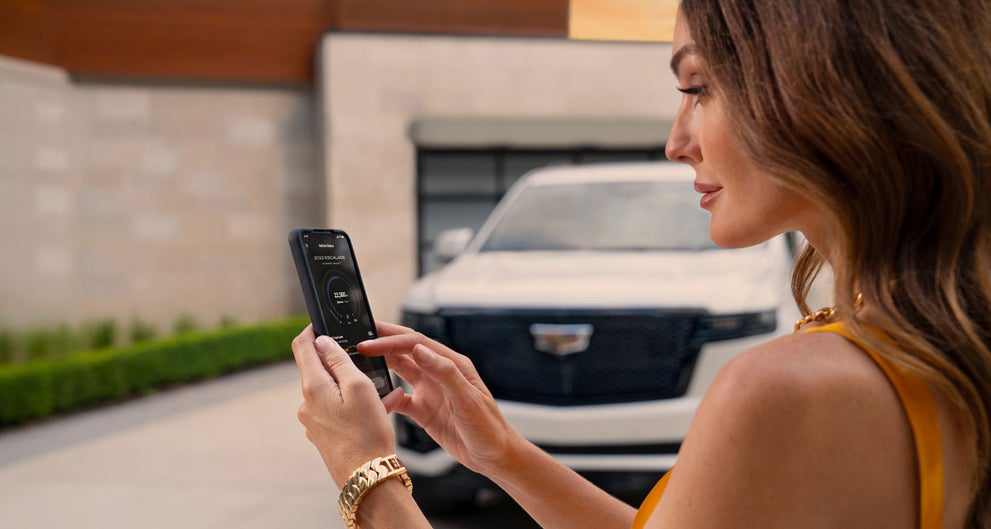 lady checking her mobile with a Cadillac vehicle background | Bergstrom Cadillac of Manitowoc in MANITOWOC WI